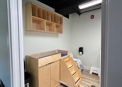 Bright, modern childcare room with wooden storage and play stairs.