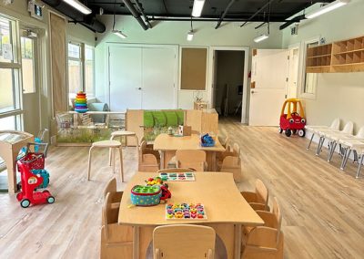 Childcare learning space with tables, toys, and cozy areas for young children to play and learn.