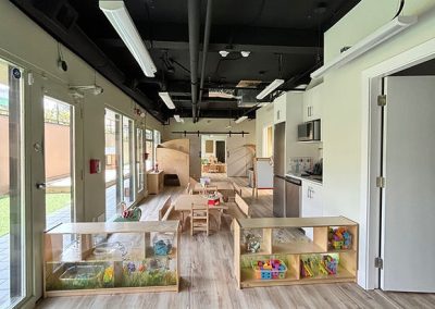 Spacious, modern indoor childcare center with toys, activity zones, and natural light.