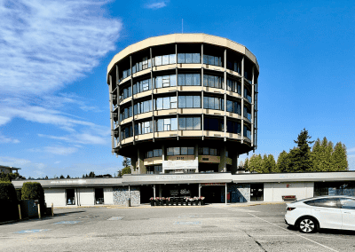 Mid-century modern McCallum Tower building with glass windows, urban parking lot, and parked white car.
