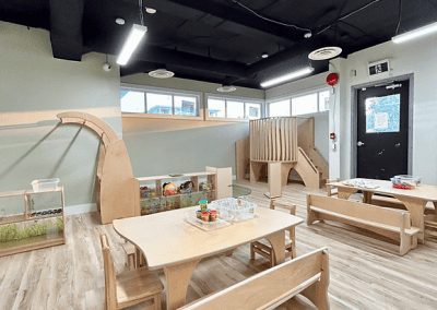 Bright, modern indoor play area with wooden furniture and activity zones.