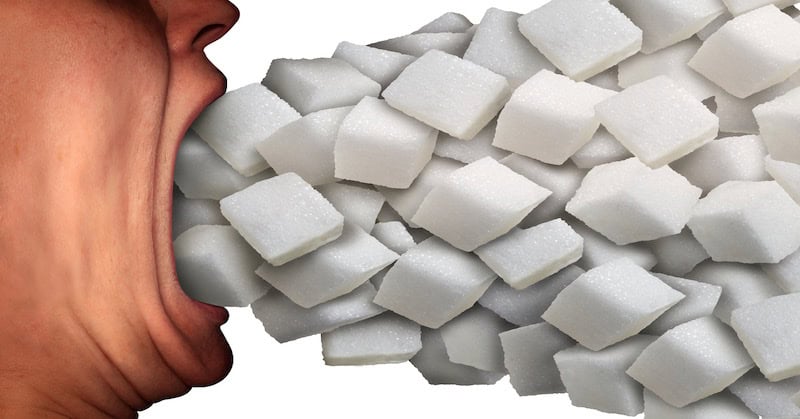 Close-up of a person’s mouth appearing to eat a large pile of sugar cubes, illustrating the concept of sweet cravings or sugar consumption.