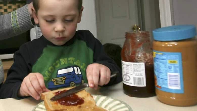 Child spreading jam on toast at a child care center.